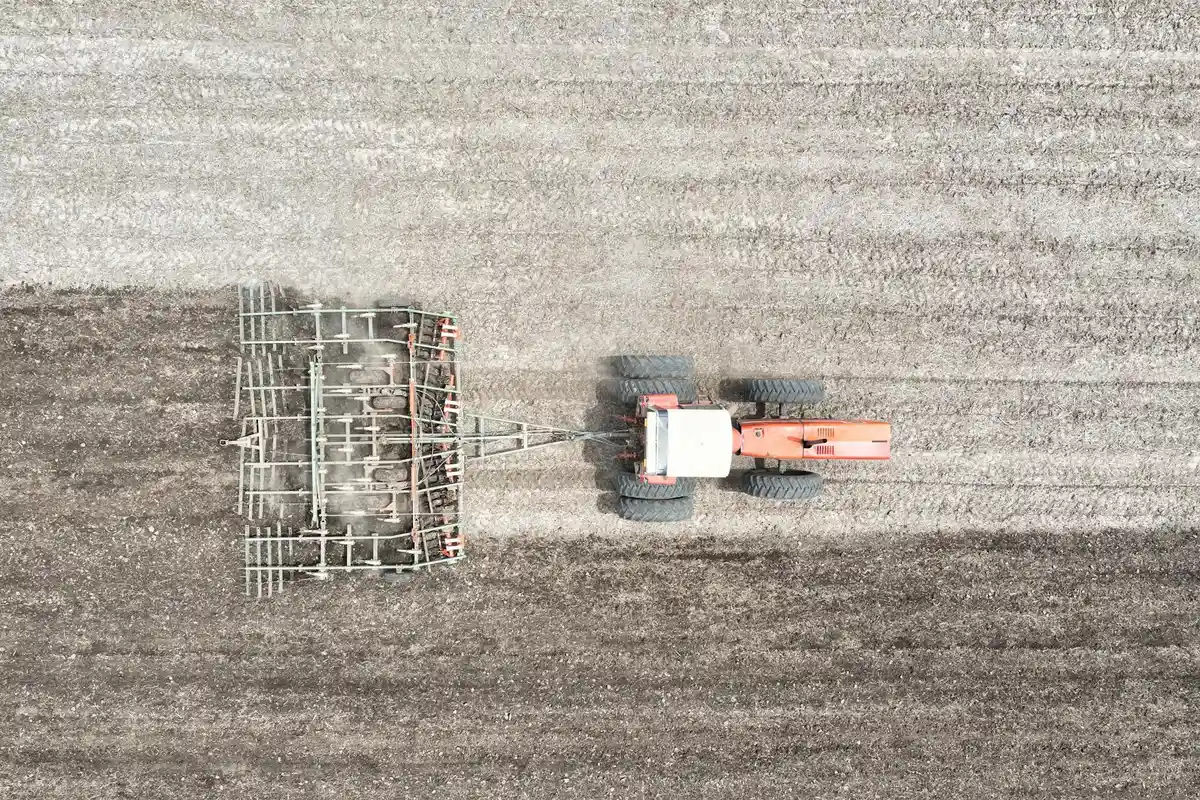 Aerial view of a tractor pulling an aeration implement across a field, showing the equipment used to relieve soil compaction.