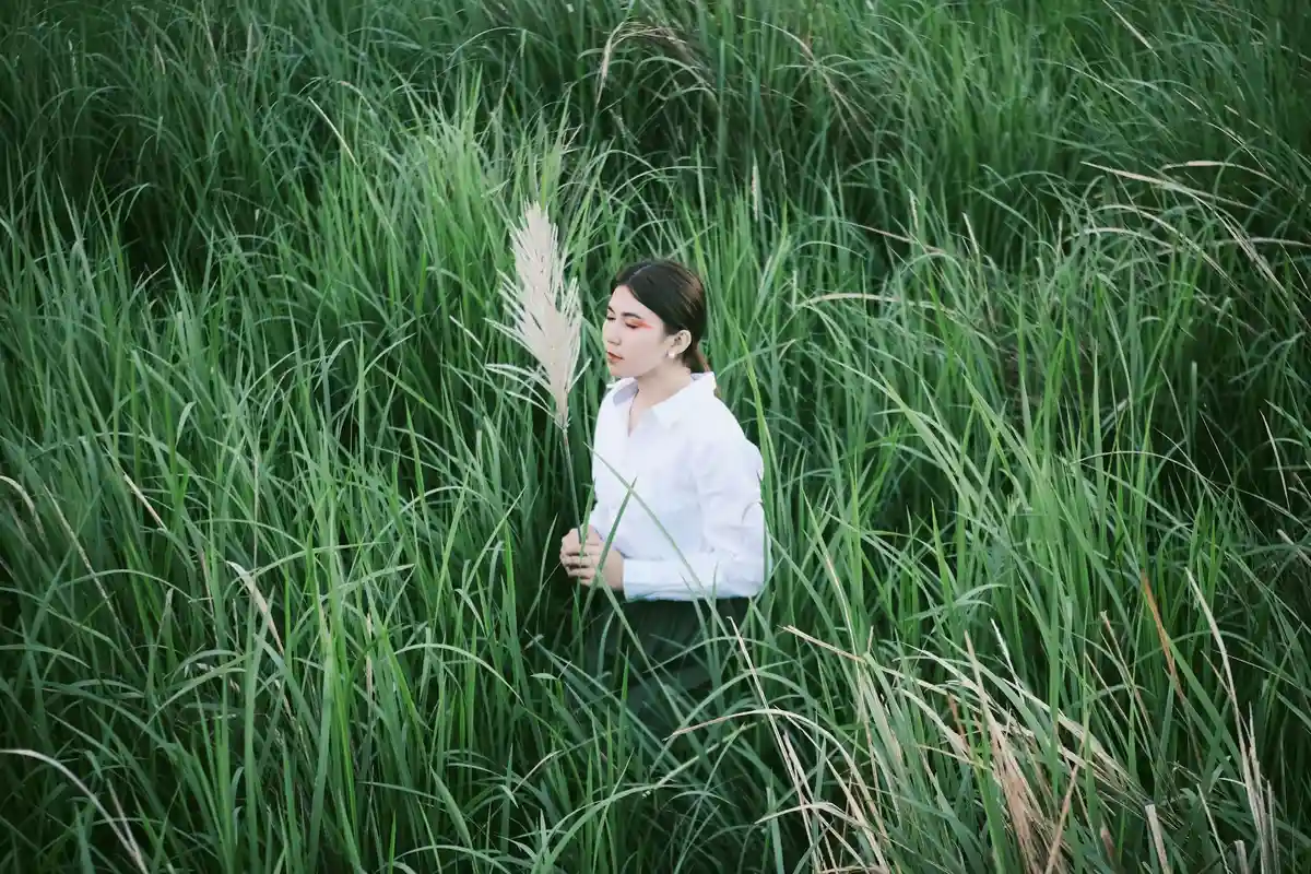 Person standing among tall, lush Bermuda grass in a field
