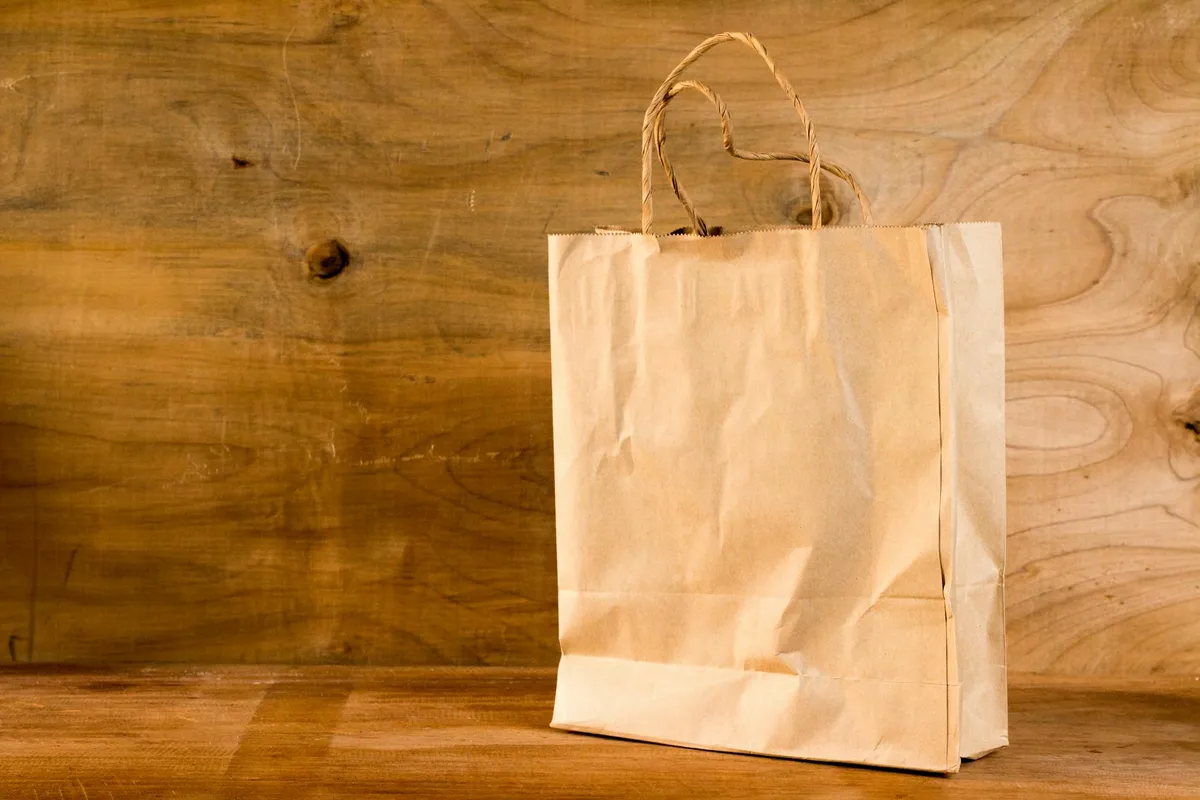 Plain brown paper bag on a wooden surface, representing storage of leftover fertilizer.