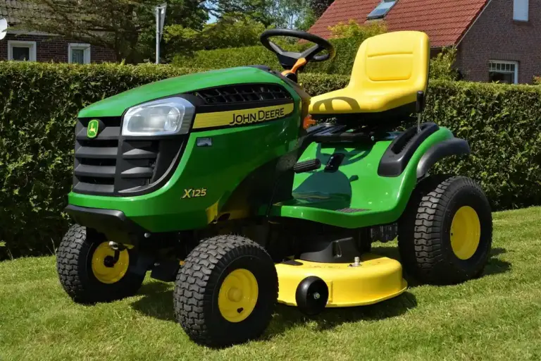 Green John Deere riding lawn mower with a yellow seat on a grassy lawn.