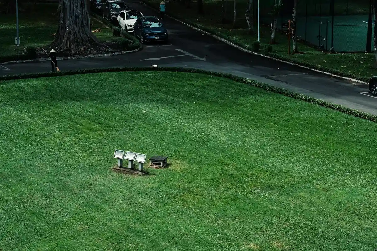 Aerial view of a lush green lawn with a small platform of outdoor floodlights, illustrating lawn maintenance work.