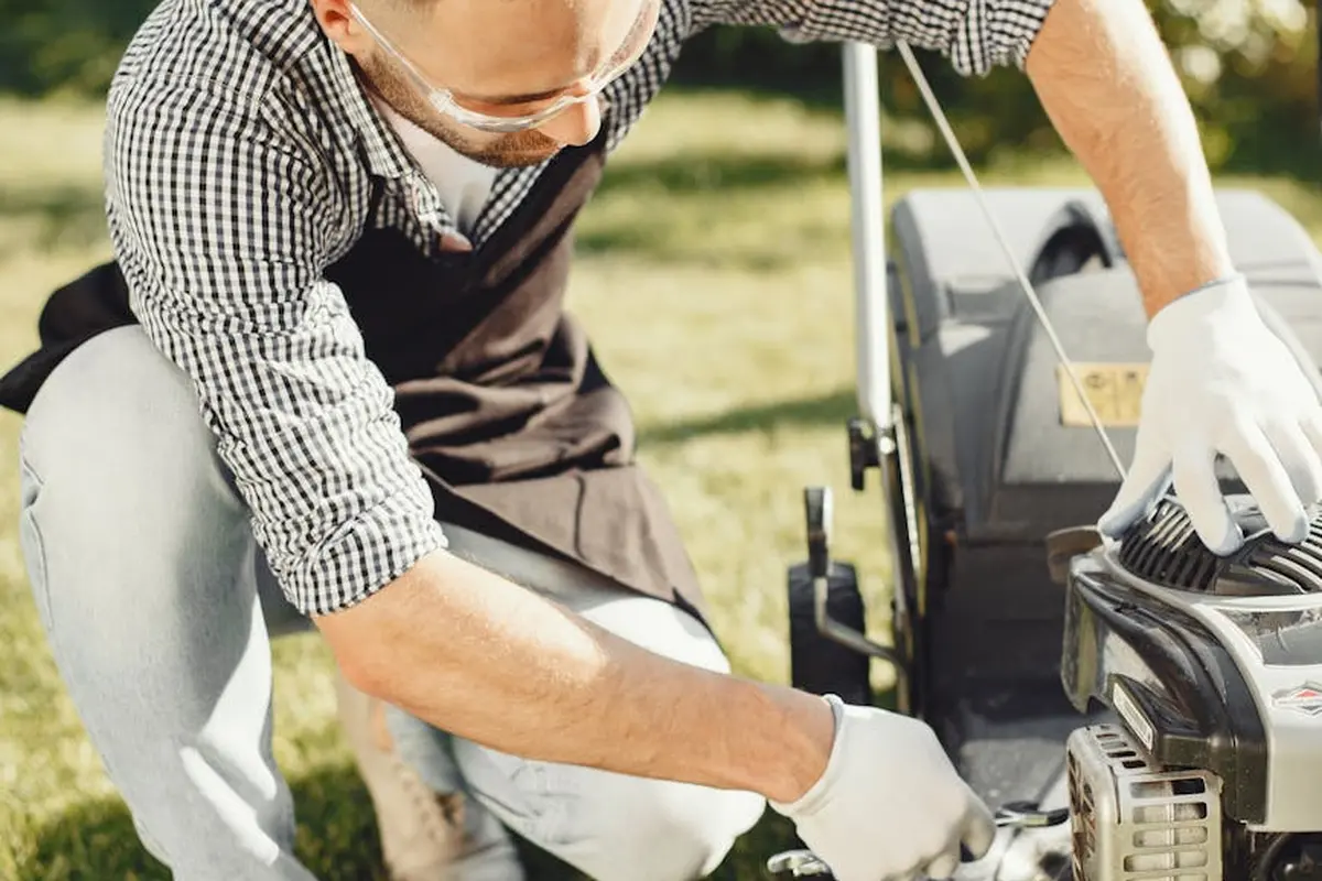 Close-up of a person wearing gloves inspecting a lawn mower blade.