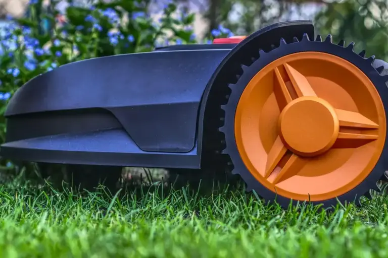 Close-up image of an orange-wheeled lawn mower resting on green grass
