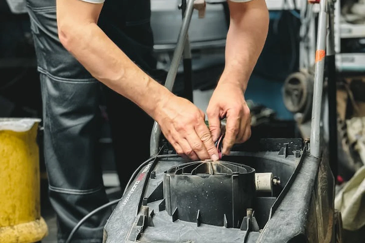 A technician adjusts a lawn mower engine in a workshop
