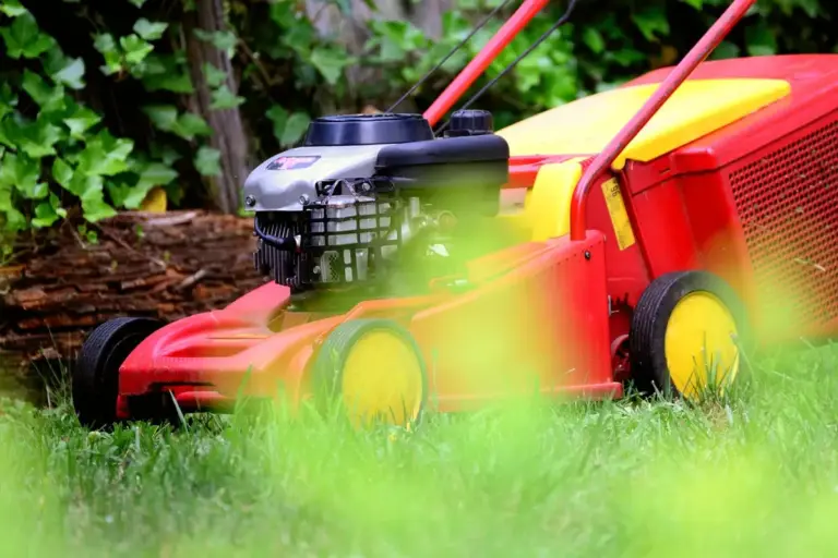 Red lawn mower on a green lawn with a blurred foreground and foliage in the background, ready for winter storage.