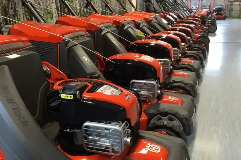 Row of red and gray lawn mowers lined up in a showroom or workshop.