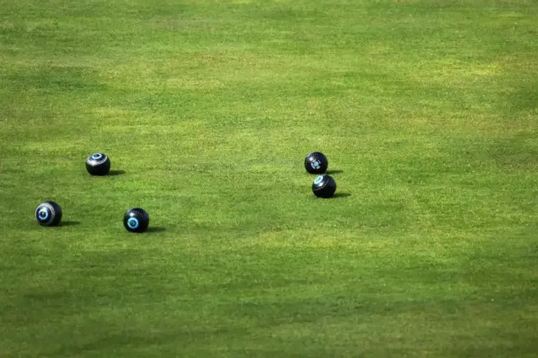 A well-kept lawn with several lawn bowls scattered across the grass