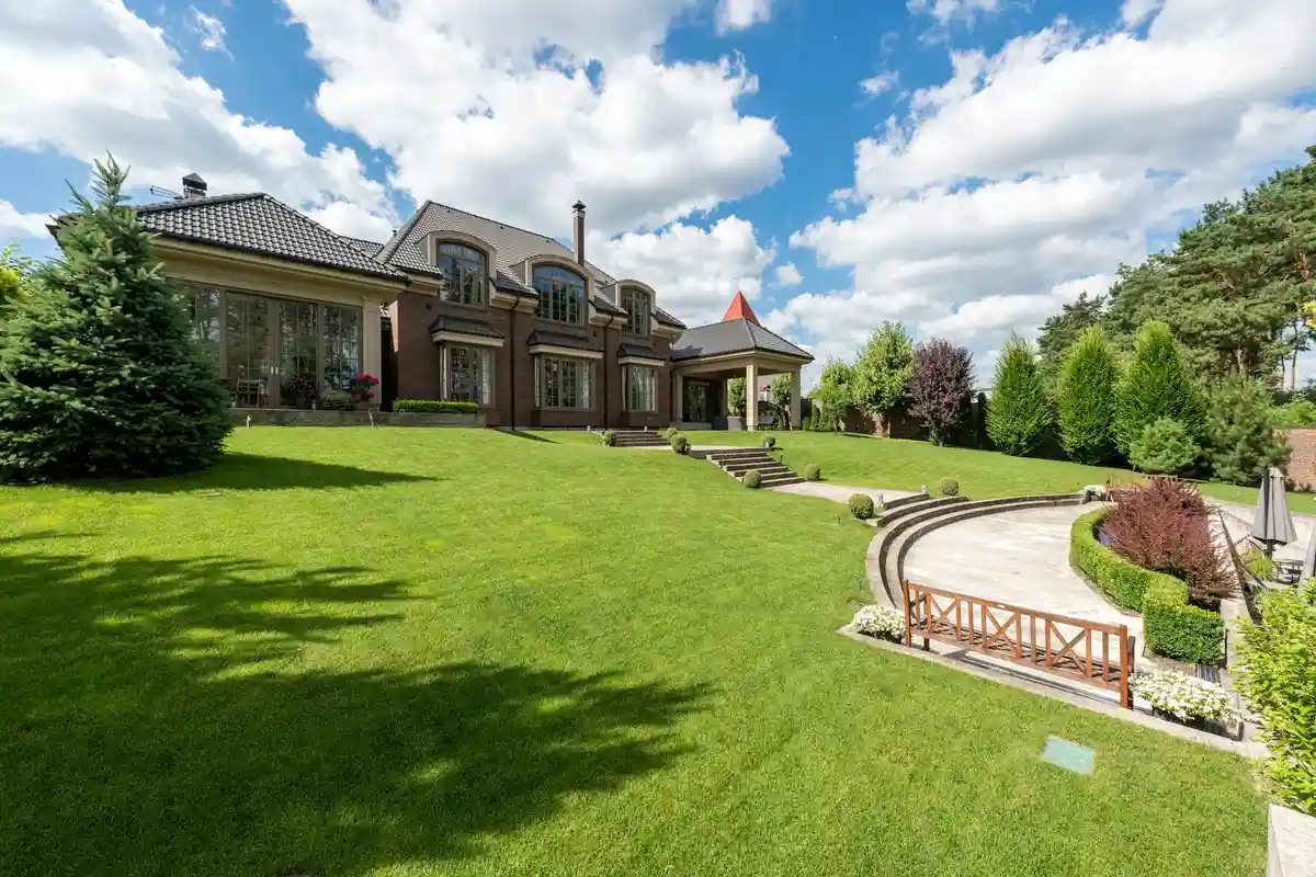Manicured front lawn with curved stone path and a large house, illustrating lawn care decision-making