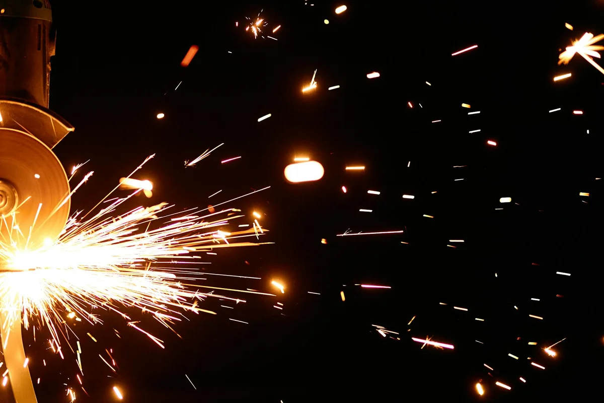 Bright sparks flying from metal during grinding, a visual metaphor for ignition concepts related to spark plugs