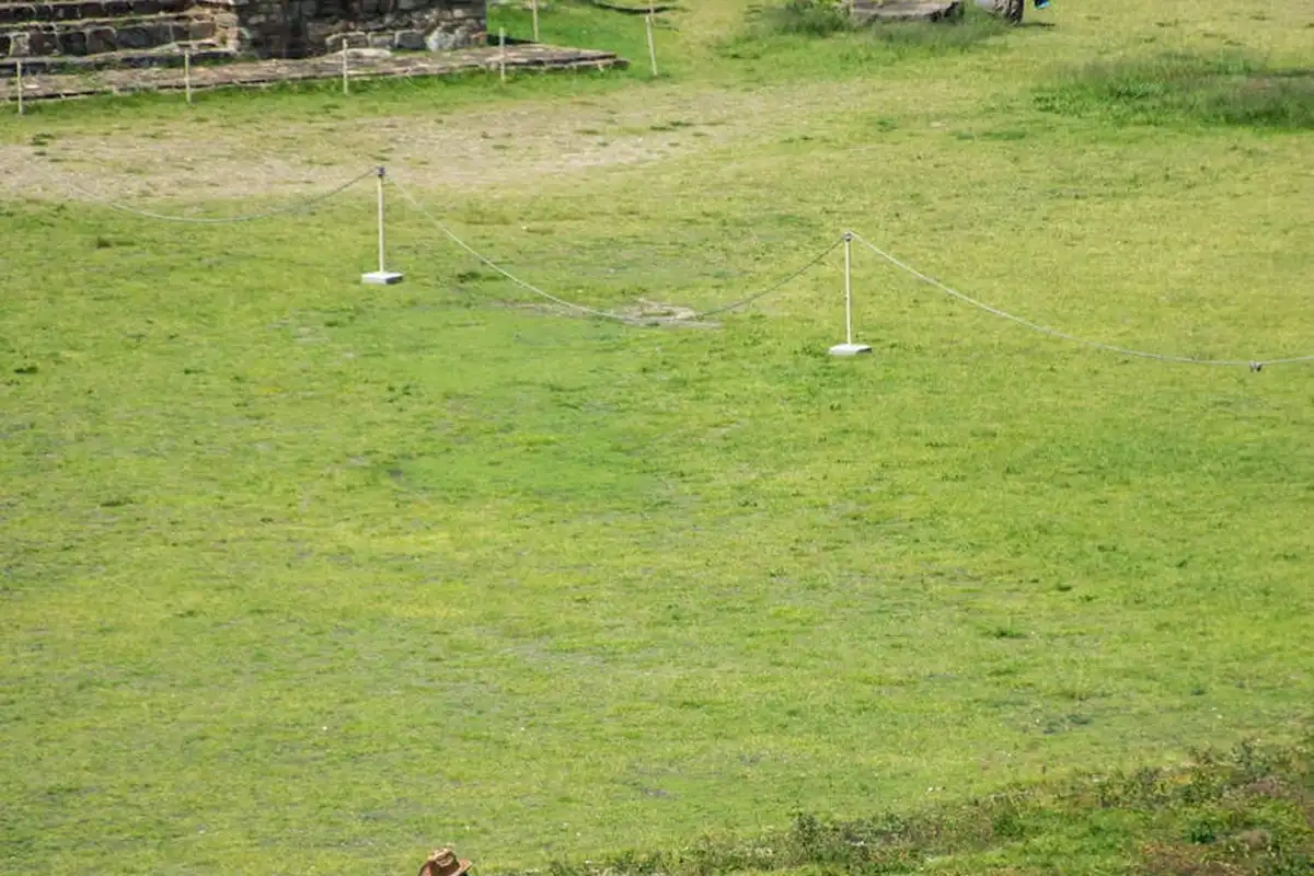Green lawn with a few white posts connected by ropes in the background