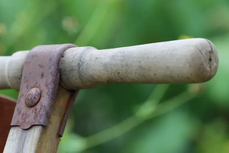 Close-up of a worn lawn mower handle with a rusted metal bracket