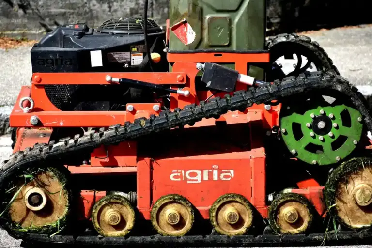 Close-up of a red tracked lawn aerator machine on grass.