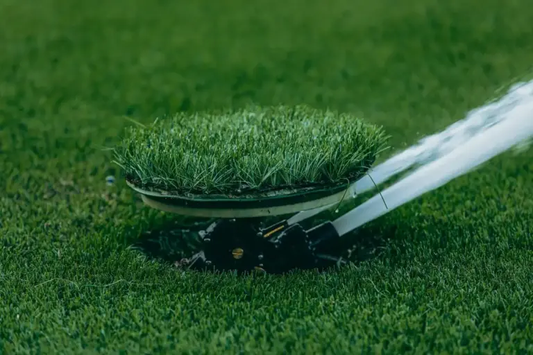 Close-up of a lawn aeration tool with a round head resting on a lush green lawn