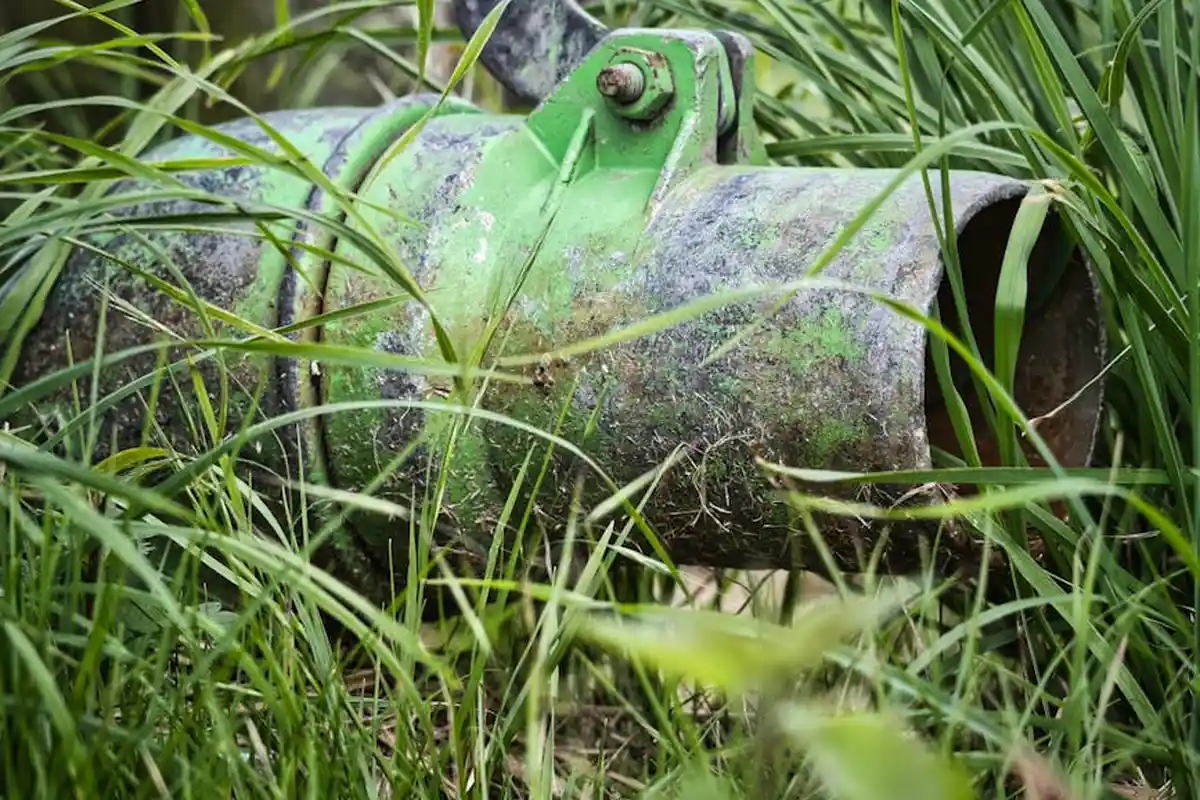 A green sprinkler head partially obscured by tall, lush grass in a lawn.