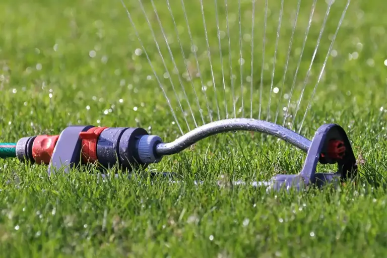 A lawn sprinkler waters a lush green lawn.