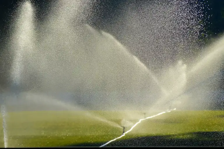 Sprinklers watering a lush green lawn, creating arcing water streams.