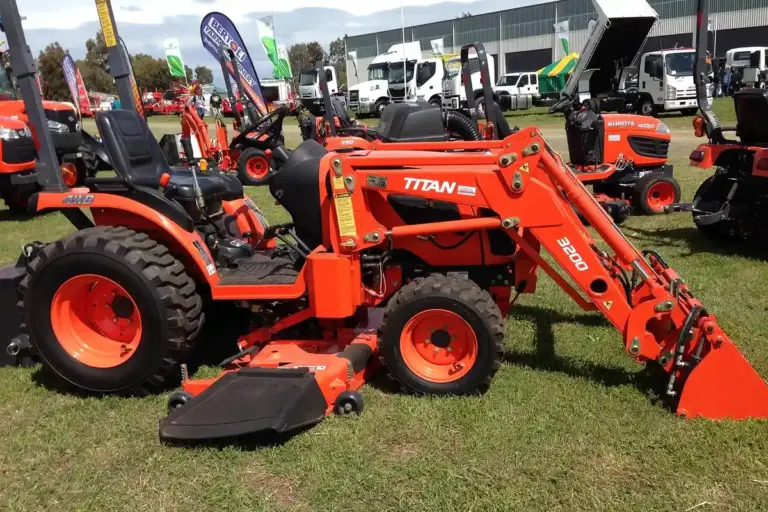 Red lawn tractors with front-end loader attachments on display at an outdoor equipment show.