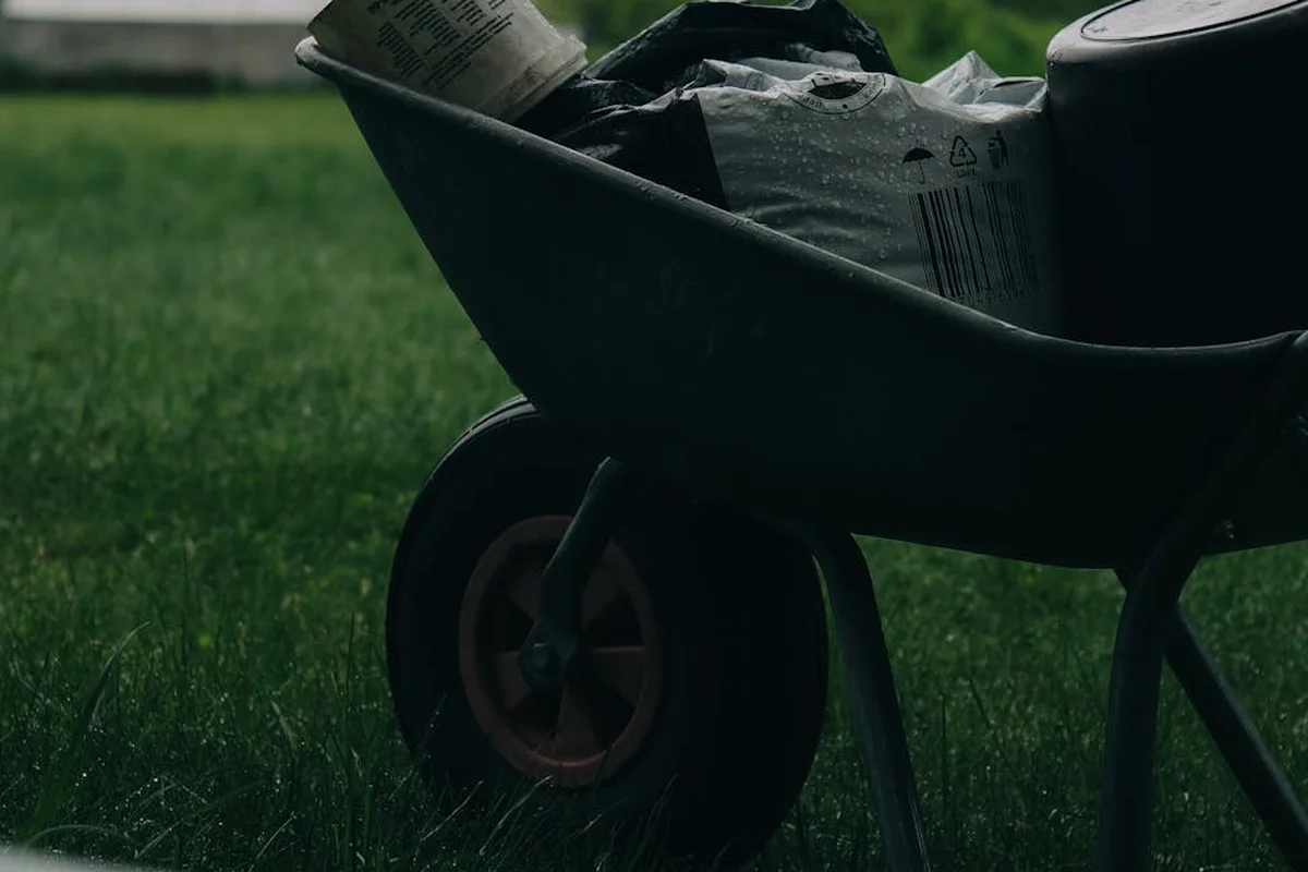 Wheelbarrow filled with bags of lawn fertilizer resting on a green lawn