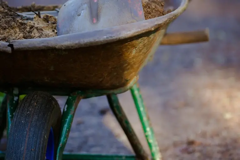 Wheelbarrow loaded with soil at a garden site, ready for use.
